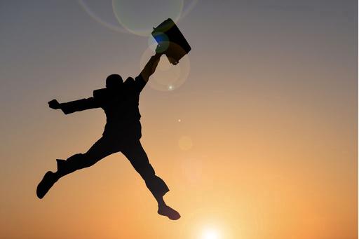 Business man jumping in air at sunset