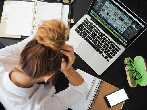 woman with her head in her hands surrounded by work