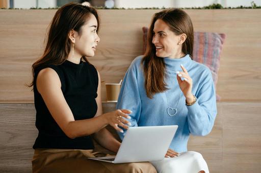 two woman talking together with a laptop