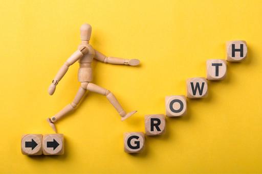 wooden man climbing stairs representing growth